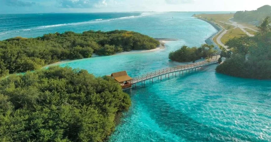 An aerial view of green islands, a turquoise channel and a long bridge across the lagoon